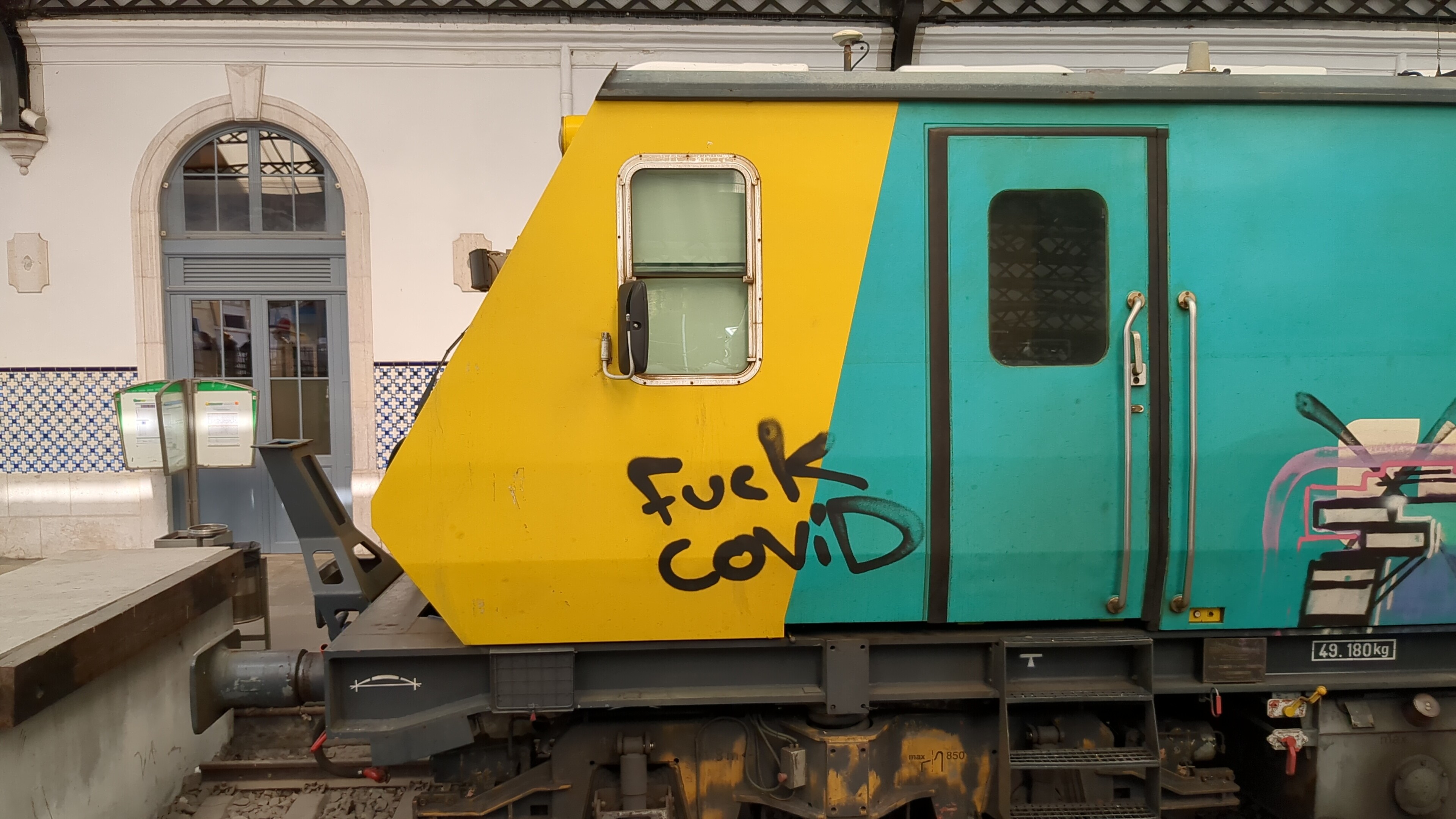 The side of a train with a graffitti saying Fuck Covid