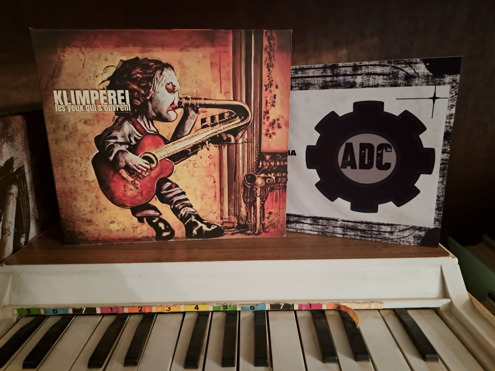 Klimperei's latest release of his toy music, over a toy piano, in front of an ADC postcard (ADC being the label that released this album).