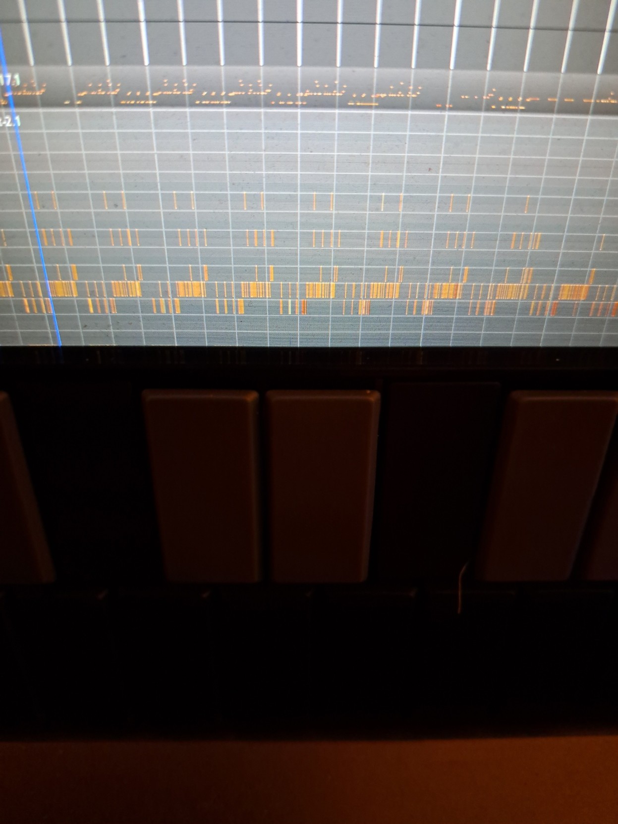 A picture taken in a dark studio, a keyboard in front of the source of light: a screen where ardour can be seen in use, with two midi tracks on it.