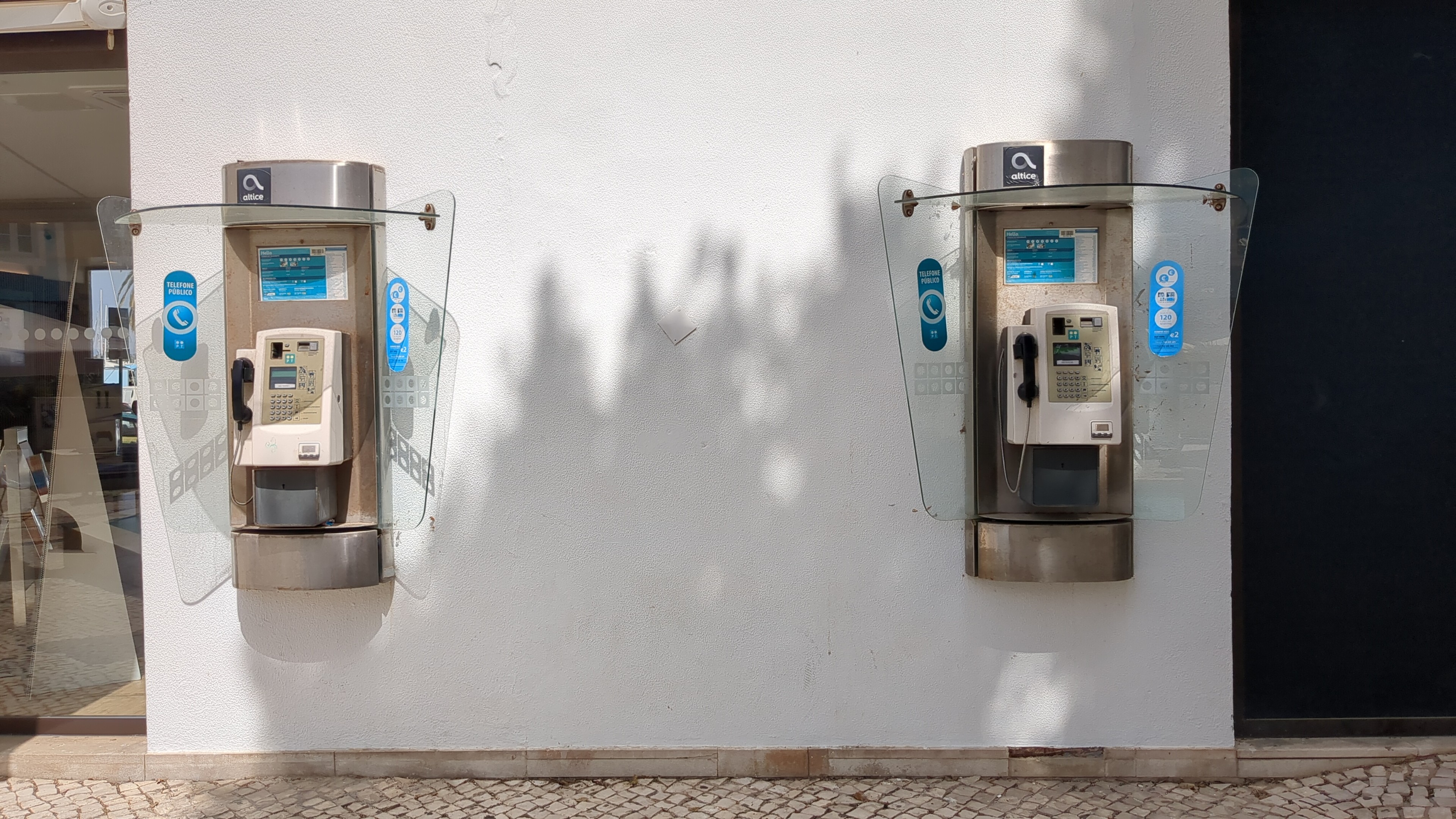 Uma parede branca com dois telefones públicos