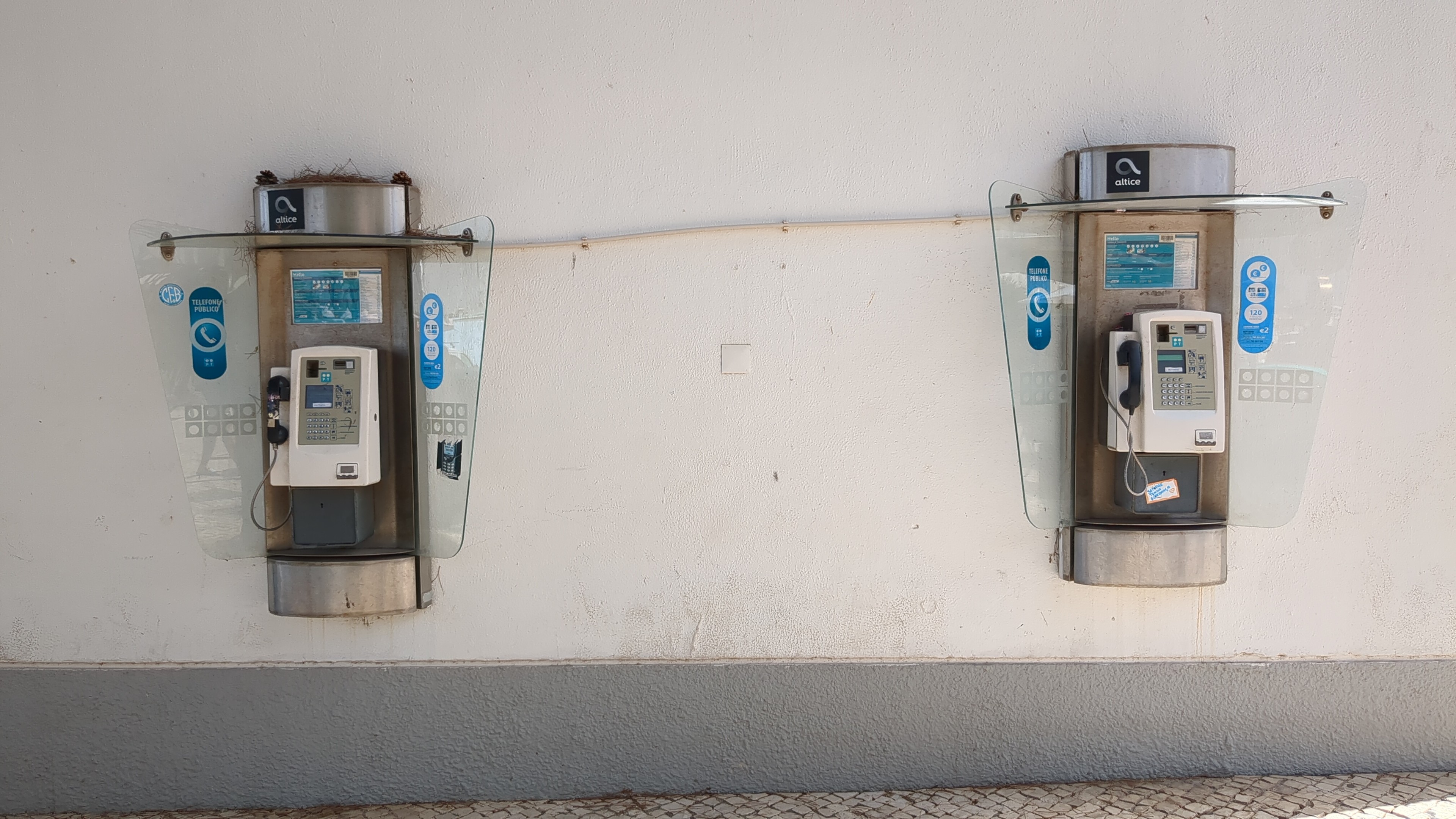 Dois telefones públicos numa parede branca