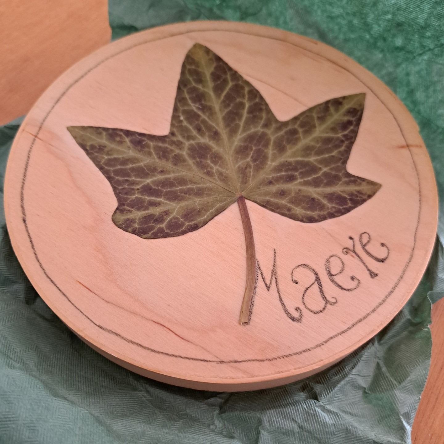 Maere - a compilation CD in a round wooden box with a maere leaf, and &lsquo;Maere&rsquo; written with pencil.